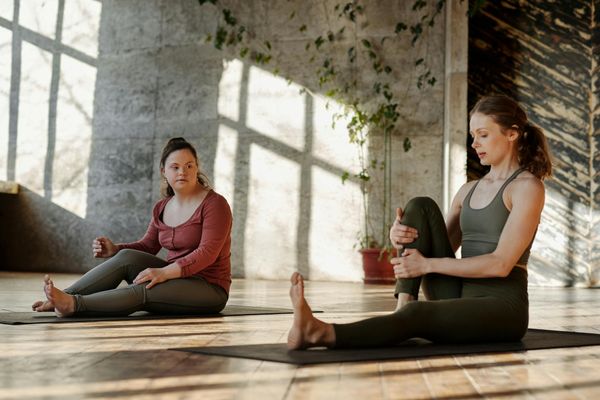 Person stretching on a yoga mat in a bright, sunlit room.